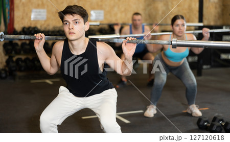 Motivated CrossFit male athlete lifting heavy body bar or barbell during group training in gym. Functional training concept 127120618