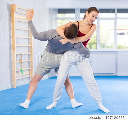 Young girl practicing self-defense techniques in pair with middle-aged man 127120635
