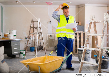 Confused man builder with documentation in apartment Confused man builder with documentation in apartment 127120697