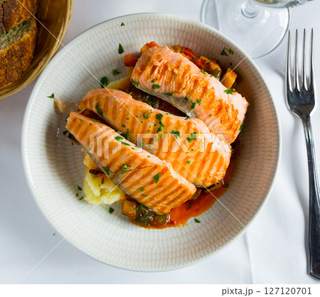 Tasty steak of grilled salmon in sauce with pepper and lemon on plate 127120701