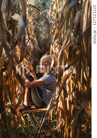 Young Girl Sitting Thoughtfully in a Cornfield Young Girl Sitting Thoughtfully in a Cornfield 127121222
