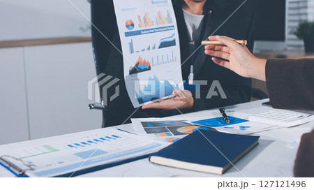 Focused young businessman signing agreement with skilled lawyer in eyeglasses. Concentrated financial advisor showing place for signature on paper contract document to male client at meeting in office Focused young businessman signing agreement with skilled lawyer in eyeglasses. Concentrated financial advisor showing place for signature on paper contract document to male client at meeting in office 127121496