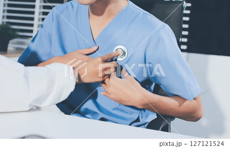 A physician uses a stethoscope to examine a patient's heart during a clinic appointment. A physician uses a stethoscope to examine a patient's heart during a clinic appointment. 127121524