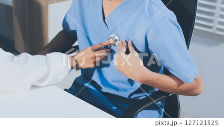 A physician uses a stethoscope to examine a patient's heart during a clinic appointment. A physician uses a stethoscope to examine a patient's heart during a clinic appointment. 127121525