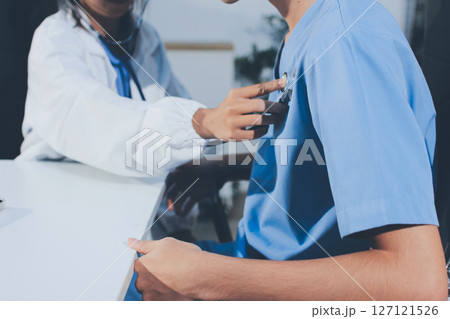 A physician uses a stethoscope to examine a patient's heart during a clinic appointment. A physician uses a stethoscope to examine a patient's heart during a clinic appointment. 127121526