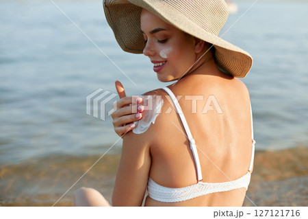 Sun cream on tanned shoulder with sun shape . Sun protection. Beautiful woman in bikini applying  Solar Cream. Skin and body care.Portrait of female holding suntan lotion 127121716