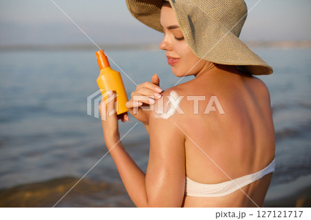 Sun cream on tanned shoulder with sun shape . Sun protection. Beautiful woman in bikini applying Solar Cream. Skin and body care.Portrait of female holding suntan lotion Sun cream on tanned shoulder with sun shape . Sun protection. Beautiful woman in bikini applying Solar Cream. Skin and body care.Portrait of female holding suntan lotion 127121717