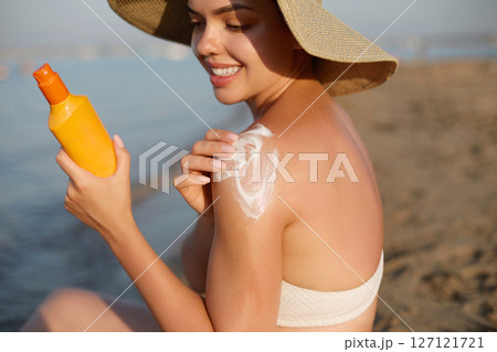 Sun cream on tanned shoulder with sun shape . Sun protection. Beautiful woman in bikini applying  Solar Cream. Skin and body care.Portrait of female holding suntan lotion 127121721