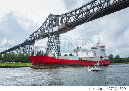 A cargo ship and a sailboat at the Rendsburg High Bridge on Kiel Canal A cargo ship and a sailboat at the Rendsburg High Bridge on Kiel Canal 127121890