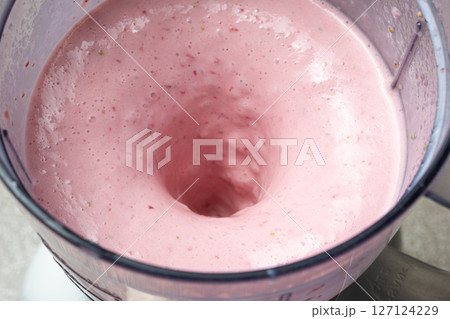 The process of making a strawberry milkshake, whisking all the ingredients in a blender. 127124229