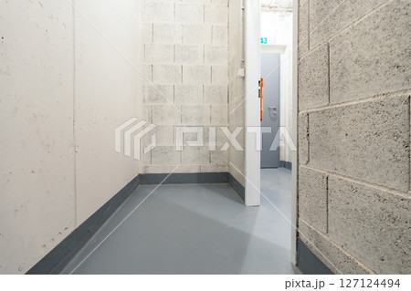 Small utility storage room with concrete walls and exit door in modern basement facility Small utility storage room with concrete walls and exit door in modern basement facility 127124494