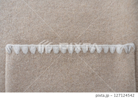 Decorative pocket stitching on beige wool blend coat close-up 127124542