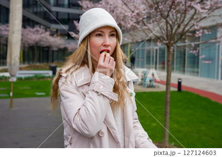 Modern elegance: Woman enjoying pretzel in Prague city park 127124603