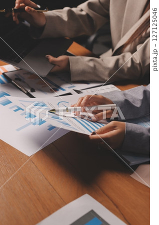Group of confident business people point to graphs and charts to analyze market data, balance sheet, account, net profit to plan new sales strategies to increase production capacity. 127125046