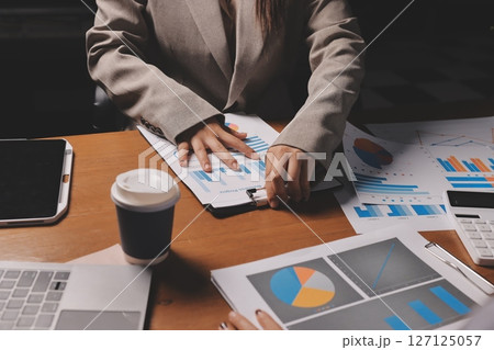 Group of confident business people point to graphs and charts to analyze market data, balance sheet, account, net profit to plan new sales strategies to increase production capacity. 127125057