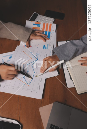 Group of confident business people point to graphs and charts to analyze market data, balance sheet, account, net profit to plan new sales strategies to increase production capacity. Group of confident business people point to graphs and charts to analyze market data, balance sheet, account, net profit to plan new sales strategies to increase production capacity. 127125062
