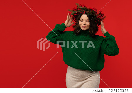 Woman wearing festive wreath of red berries and pine branches. Woman wearing festive wreath of red berries and pine branches. 127125338