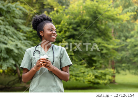 Smiling positive african american burse having coffee in the park Smiling positive african american burse having coffee in the park 127126154