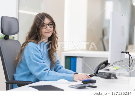 Young office worker typing on keyboard and smiling in modern office 127126234