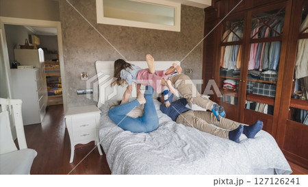 Family enjoying playful moments on bed together 127126241