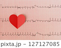 Heartbeat line with red heart shape on red grid background. 127127085