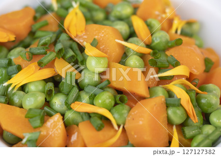 Fresh garden peas and carrots cooked in butter, garnished with chives and marigold flowers for a 127127382