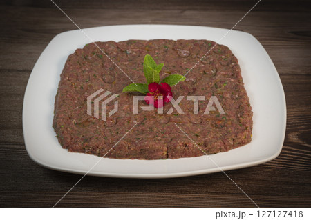 Delicious Lebanese Kebbe Naye garnished with olive oil and fresh mint on a rustic wooden table 127127418