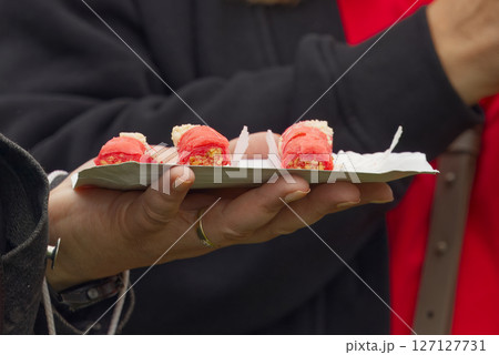 Person Holding a Plate of Appetizing Red Snacks on a Casual Occasion Person Holding a Plate of Appetizing Red Snacks on a Casual Occasion 127127731