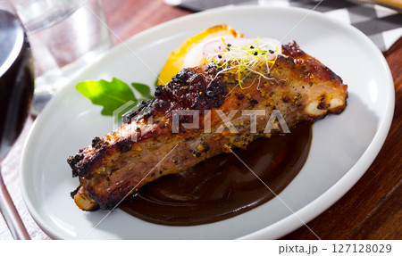 Roasted pork ribs in chocolate sauce with baked potatoes 127128029