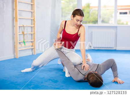 Young woman learns to do painful grip on arm of an attacking man during self defense training Young woman learns to do painful grip on arm of an attacking man during self defense training 127128133