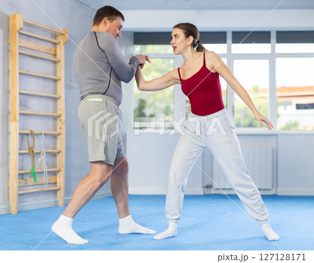 Young woman learns to do painful grip on arm of an attacking man during self defense training Young woman learns to do painful grip on arm of an attacking man during self defense training 127128171