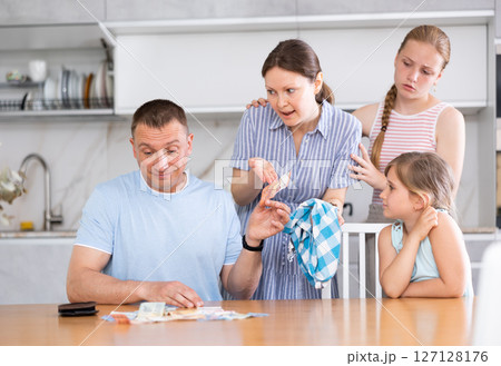 Dissatisfied husband and father give out pocket money to wife and children in kitchen Dissatisfied husband and father give out pocket money to wife and children in kitchen 127128176