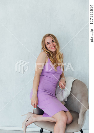 Beautiful woman in purple dress on chair laughing Beautiful woman in purple dress on chair laughing 127131614