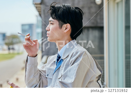 外でタバコを吸う若い男性 127131932