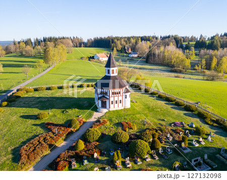 Set against a lush green landscape, Tesarov Chapel features a distinctive octagonal design. Its striking white exterior stands out in the serene surroundings of Korenov, Czechia, during a clear day. 127132098