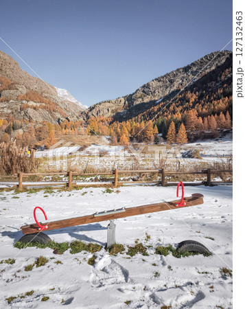 Snow covering wooden seesaw near mountain landscape, vibrant autumn foliage framing scenic valley in aosta, italy Frazionne Lillaz Snow covering wooden seesaw near mountain landscape, vibrant autumn foliage framing scenic valley in aosta, italy Frazionne Lillaz 127132463