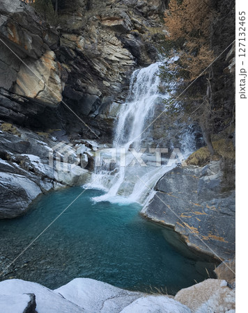 Cascading waterfall plunging into turquoise pool, rocky landscape framing verdant forest scene in aosta valley, italian alpine setting Cascate di Lillaz 127132465