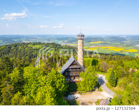 Explore the breathtaking aerial perspective of Svatobor Lookout Tower surrounded by lush greenery, offering panoramic views of the rolling hills and vibrant fields in Czechia. Explore the breathtaking aerial perspective of Svatobor Lookout Tower surrounded by lush greenery, offering panoramic views of the rolling hills and vibrant fields in Czechia. 127132504