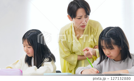 勉強する二人の女の子と厳しく指導する女性 127132880
