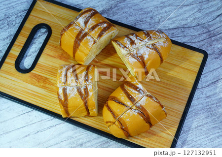 Pieces of a sweet mocha golden loaf with chocolate drizzle and powdered sugar on a wooden board. Pieces of a sweet mocha golden loaf with chocolate drizzle and powdered sugar on a wooden board. 127132951