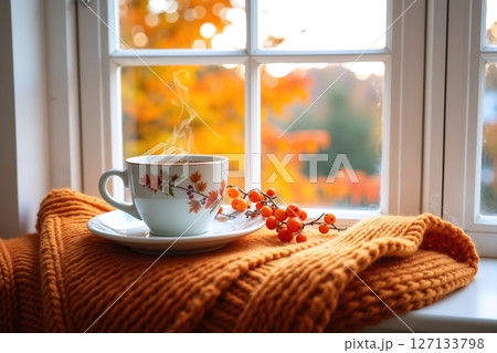 Steaming cup on a windowsill with autumn view. 127133798