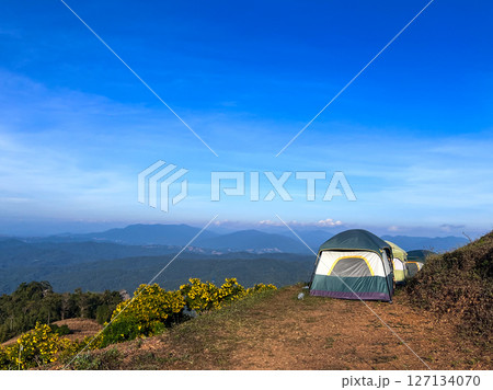 Row of tents located on the top of the hill with the panorama view of mountain and clear blue sky in background 127134070