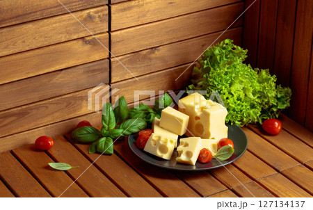 Swiss cheese, green basil, salad, and tomatoes on a wooden table. Swiss cheese, green basil, salad, and tomatoes on a wooden table. 127134137