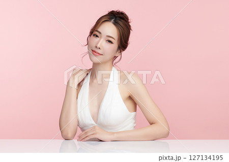 A beautiful young Asian woman with clean, fresh skin against a pink background. Skincare, facial treatment, cosmetology, beauty, and spa. An elegant portrait of an Asian woman. 127134195