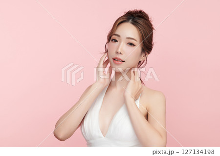 A beautiful young Asian woman with clean, fresh skin against a pink background. Skincare, facial treatment, cosmetology, beauty, and spa. An elegant portrait of an Asian woman. 127134198