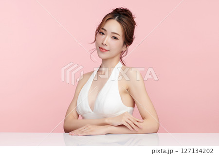 A beautiful young Asian woman with clean, fresh skin against a pink background. Skincare, facial treatment, cosmetology, beauty, and spa. An elegant portrait of an Asian woman. 127134202