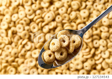 Whole grain cereal rings in a metal spoon of above cereal loops as background. Copy space for text. Whole grain cereal rings in a metal spoon of above cereal loops as background. Copy space for text. 127134543