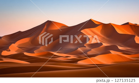 Golden hour light illuminates the majestic, undulating dunes of a vast desert landscape 127135125