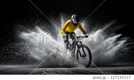 A mountain biker in a yellow jacket skillfully navigates a snowy terrain, creating a dramatic splash of snow and ice 127135127