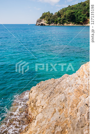Rocky coastline meets vibrant turquoise sea. Coastal scenery, summer nature, and serene outdoor exploration. 127135198